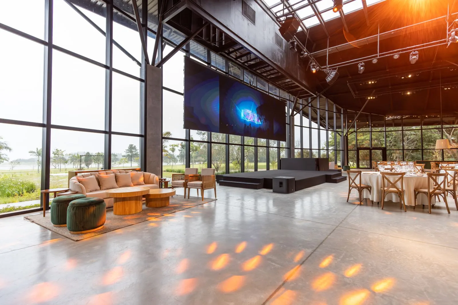 Wide event venue with large windows, a stage and orderly seating